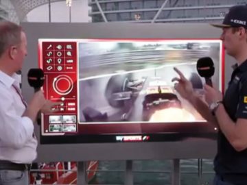 Twee mannen staan naast een videoscherm op een boot en tonen een masterclass regenrijden met Max Verstappen.