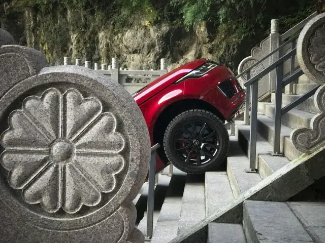 Een rode Range Rover Sport PHEV geparkeerd op een stenen trap bij Heaven’s Gate.