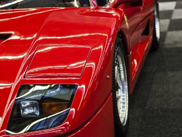 Een rode Ferrari-sportwagen staat geparkeerd in de showroom van de International Amsterdam Motor Show 2018.