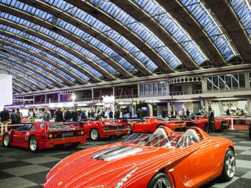 Een rode sportwagen staat geparkeerd in een grote ruimte op de International Amsterdam Motor Show 2018.