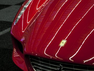 Een rode Ferrari-sportwagen staat geparkeerd op een geblokte vloer op de International Amsterdam Motor Show 2018.