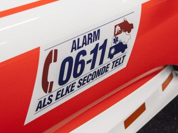 Een rood-witte vrachtwagen met een alarmsticker erop, tentoongesteld op de International Amsterdam Motor Show 2018.