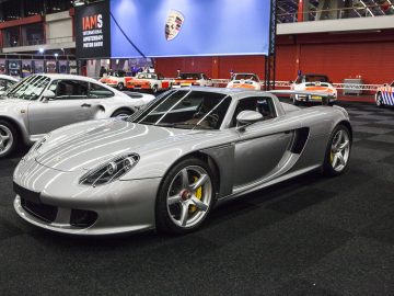 Een zilveren Porsche-sportwagen staat geparkeerd in de showroom van de International Amsterdam Motor Show 2018.