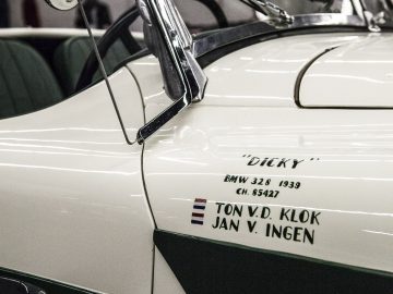 Een witte en groene klassieke auto staat geparkeerd in een garage op de International Amsterdam Motor Show 2018.
