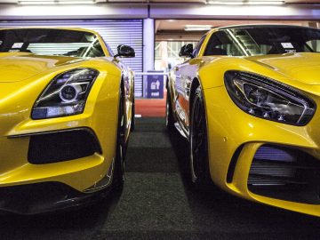 Twee gele sportwagens, tentoongesteld op de International Amsterdam Motor Show 2018, staan geparkeerd in een garage.