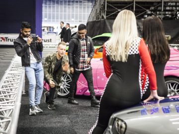 Een groep mensen staat voor een roze auto op de International Amsterdam Motor Show 2018.