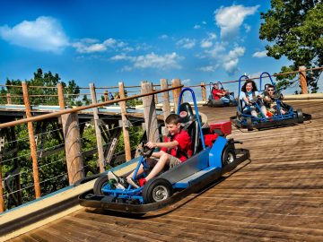 Kinderen rijden op skelters op een houten promenade, die doet denken aan Mario Kart-races.