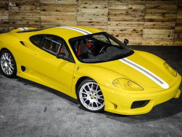 Een gele Ferrari-sportwagen staat geparkeerd voor een houten muur op de International Amsterdam Motor Show.