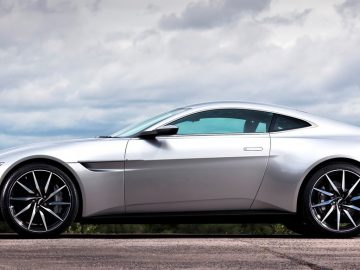 De zilveren Aston Martin Vantage-sportwagen staat geparkeerd op de weg.