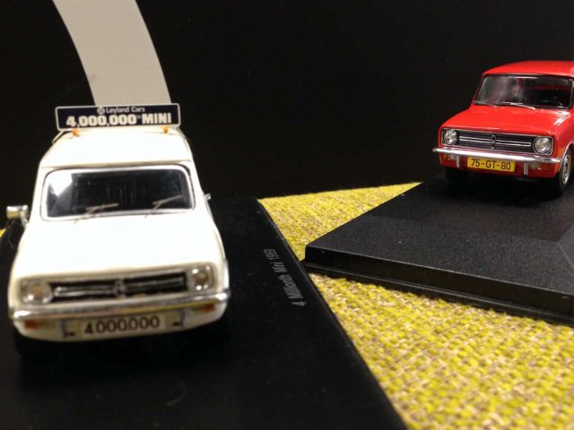 Twee miniatuur autootjes bovenop een standaard.