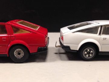 Twee Dinky Toys autootjes naast elkaar op een witte ondergrond.