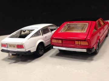 Twee Dinky Toys autootjes naast elkaar op een tafel.