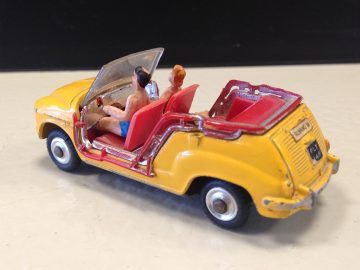 Een miniatuur speelgoedauto met twee personen erin.