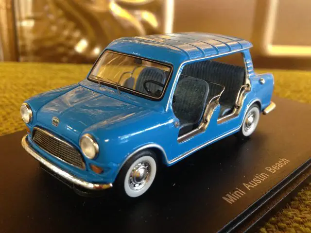 Een model van een blauwe mini-strandauto, zittend op een tafel.