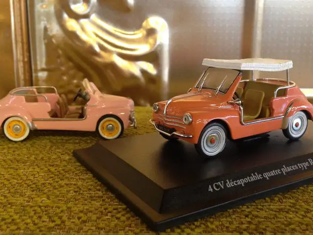 Een model van een roze auto en een model van een witte strandauto.