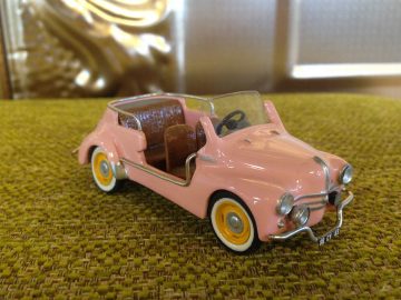 Een roze speelgoedautootje op een groen tapijt, dat doet denken aan zomer strandauto’s.