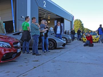 Een groep mensen die voor een groep auto's staan tijdens de Borderrun Fly-in Car Show 2017.