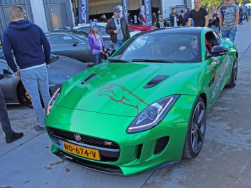 Een groene jaguar-sportwagen staat geparkeerd voor een menigte mensen op de autoshow 2017.