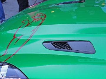 De motorkap van een groene sportwagen met een rood embleem, te zien op de Borderrun Fly-in Car Show 2017.