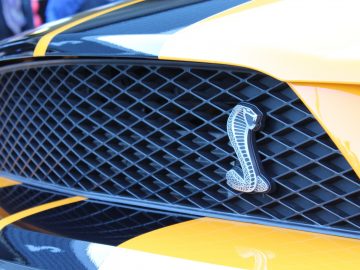 Een close-up van een gele en zwarte Mustang-grille op een autoshow.