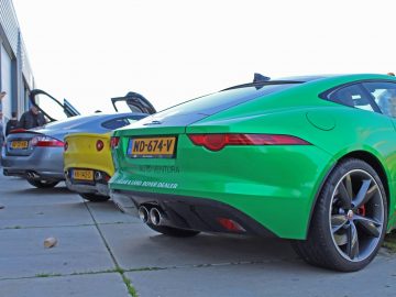 Een groene jaguarsportwagen staat geparkeerd voor een gebouw voor het Borderrun-evenement.