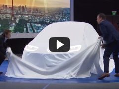 Een man in pak legt een laken over een elektrische Volkswagen-auto.