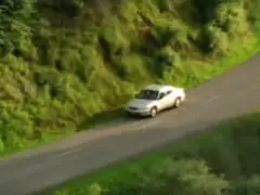 Een luchtfoto van een auto die over een kronkelige weg rijdt.