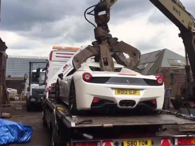 Een witte Ferrari gesloopt wordt op een dieplader geladen.