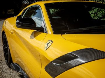 Een gele Ferrari F12tdf-sportwagen staat langs de kant van een weg in Limburg geparkeerd, te koop.