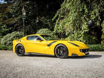 Een gele Ferrari F12tdf-sportwagen te koop geparkeerd op een grindoprit.