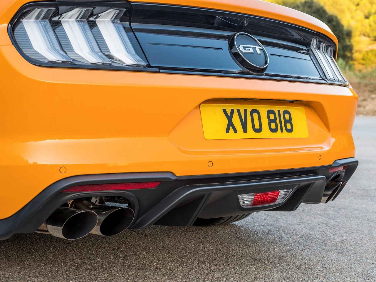 De achterkant van een oranje Ford Mustang GT.