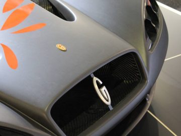 Een jaguar xkr met een zwarte grille en oranje embleem, te zien op Autosalon 2018.