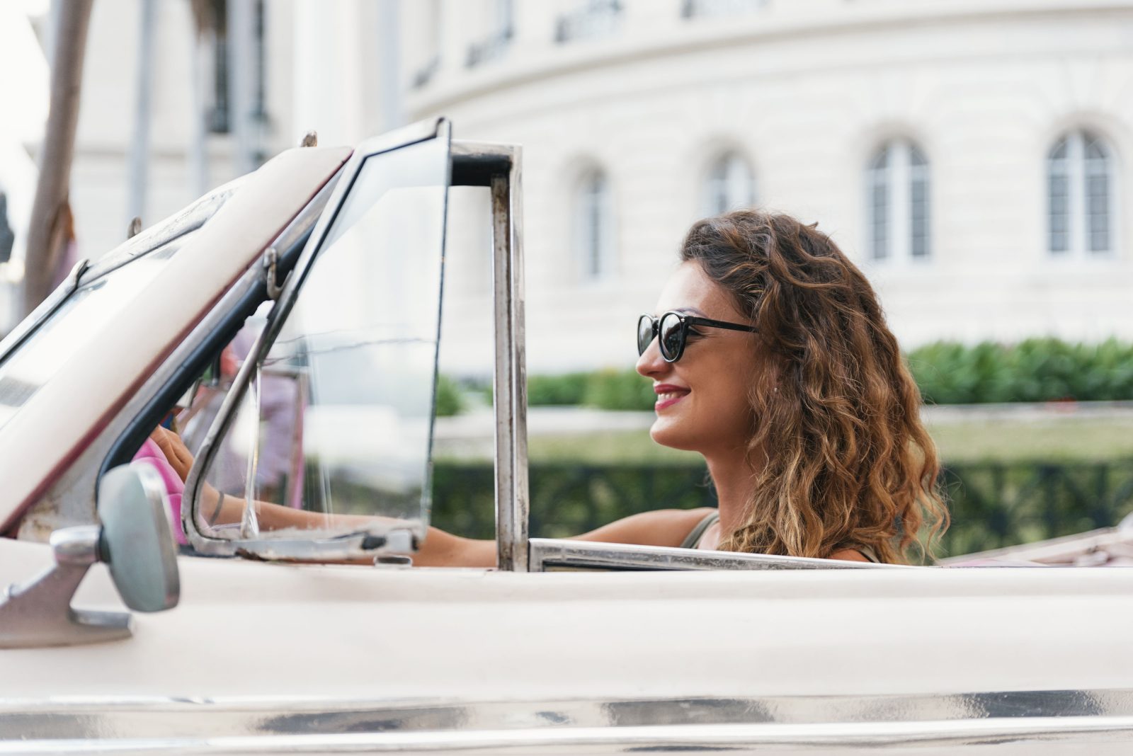 Een vrouw in zonnebril rijdt een vintage auto.