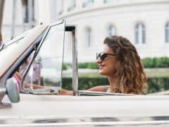 Een vrouw in zonnebril rijdt een vintage auto.