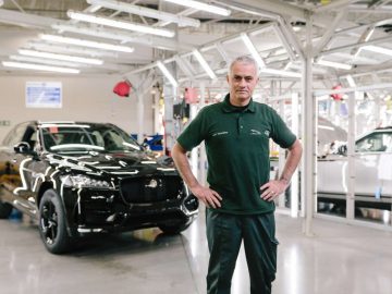 Een man die voor een Jaguars F-Pace staat in een fabriek, ter ere van het 100.000ste verkochte model.