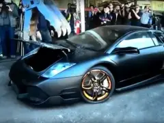 Een zwarte Lamborghini LP-640 supercar staat geparkeerd voor een menigte mensen.