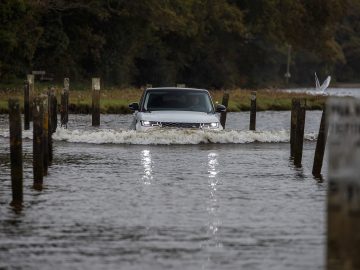 Een witte Range Rover Sport P400e rijdt door een overstroomd gebied.