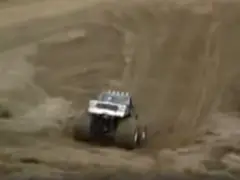Een monstertruck die over een onverharde weg rijdt op een steile helling.