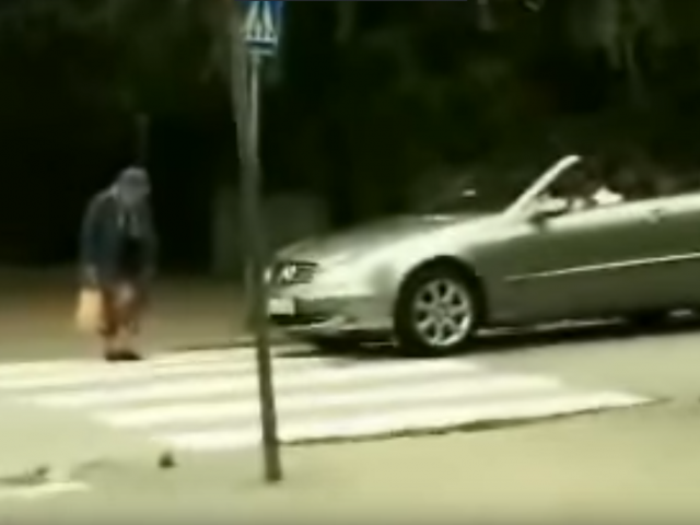 Een man steekt voor een auto de straat over en belichaamt de geest van "oma laat zich niet opjagen".