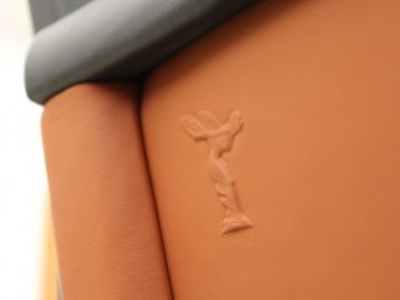 Een close-up van een leren stoel met het Rolls-Royce Phantom-logo erop.