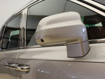 Een zijspiegel van een zilveren nieuwe Rolls-Royce SUV.
