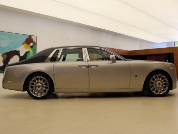 Een zilveren Rolls-Royce Phantom staat geparkeerd in een showroom.