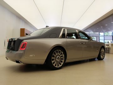 In een showroom staat een nieuwe Rolls-Royce Phantom geparkeerd.