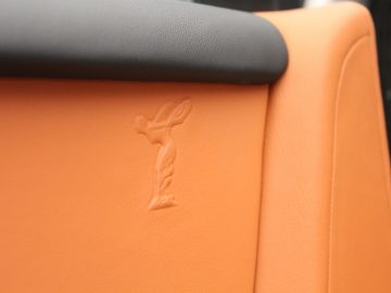 Een close-up van een nieuwe Rolls-Royce met een logo op de stoel.