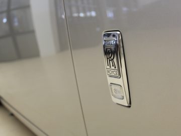 Een close-up van het Rolls-Royce Phantom-embleem op een zilveren auto.