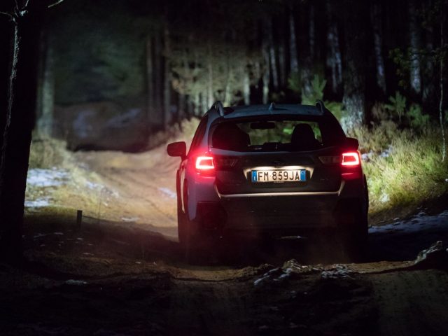 Een Subaru XV die 's nachts over een onverharde weg rijdt.
