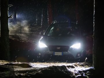 Een Subaru XV die 's nachts door het bos rijdt.