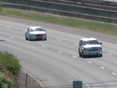 Een politieauto rijdt over de snelweg met een motorfiets op de achtergrond, vastgelegd in deze VIDEO.