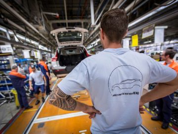 Een man in t-shirt staat naast een Volvo XC40 in de productielijn.