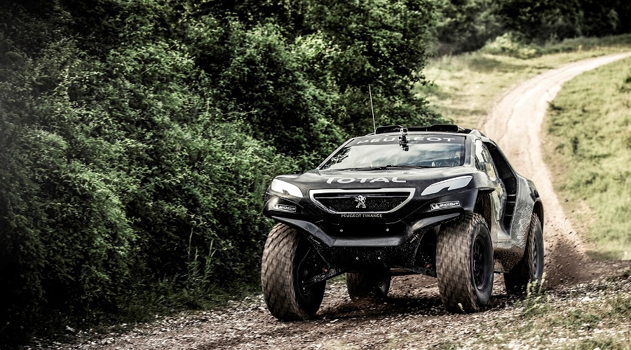Een zwarte Dakar-monstertruck rijdt over een onverharde weg.